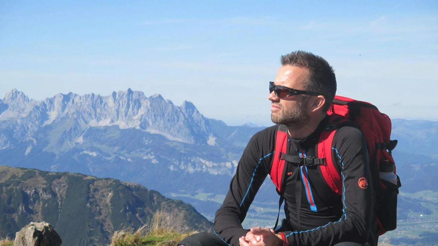 Frau steht selbstbewusst auf einem Berggipfel im Sonnenuntergang.